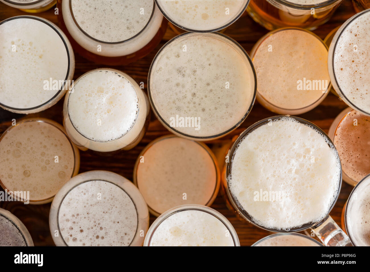An assortment of full, frothy beer glasses and sizes on a bar bench top