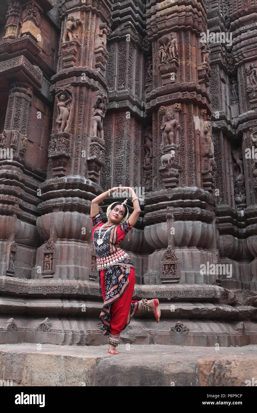 odissi is one of the eight classical dance forms of india,from the state of odisha.here the dancer poses before temples with sculptures Stock Photo