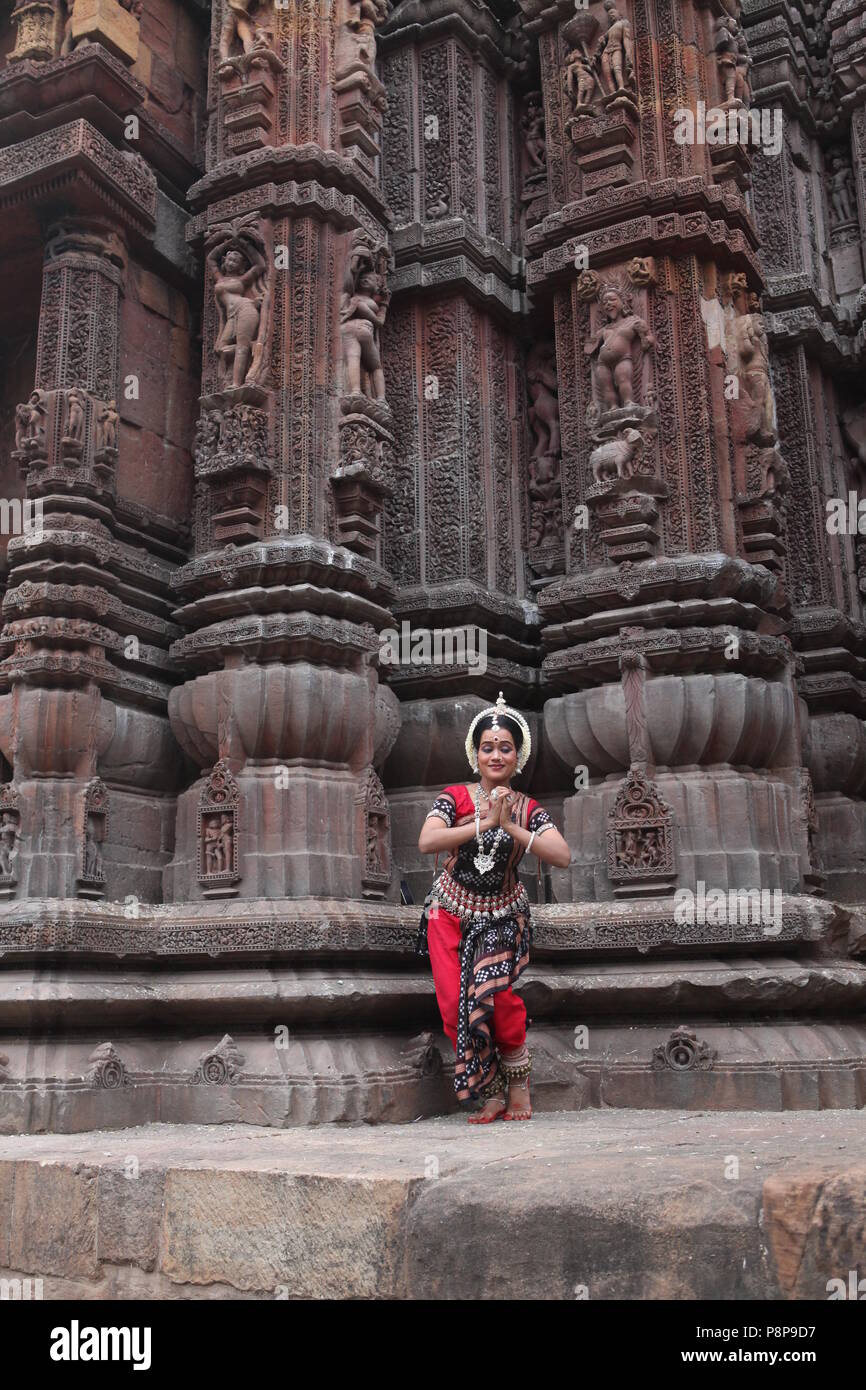 odissi is one of the eight classical dance forms of india,from the state of odisha.here the dancer poses before temples with sculptures Stock Photo