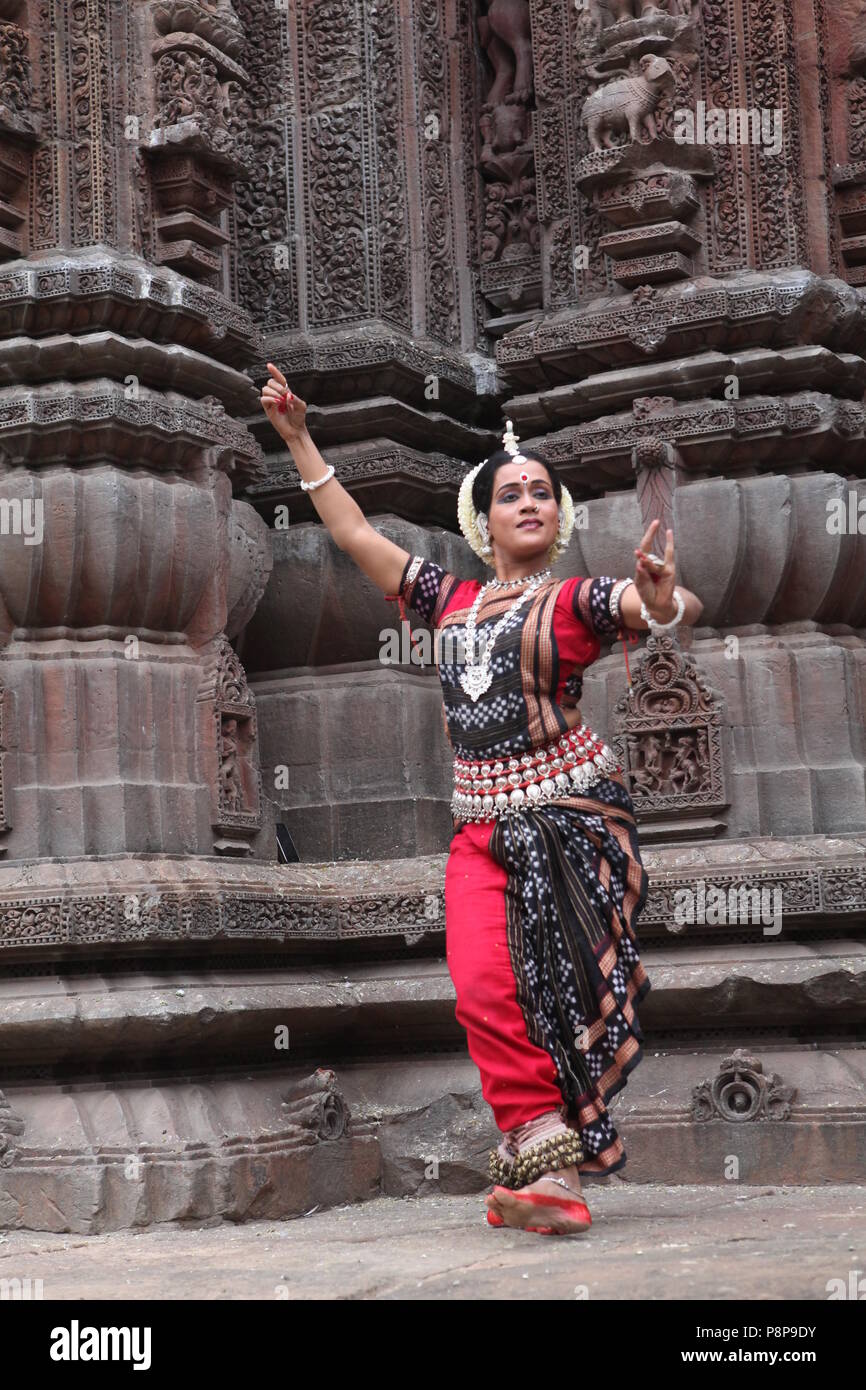 odissi is one of the eight classical dance forms of india,from the state of odisha.here the dancer poses before temples with sculptures Stock Photo