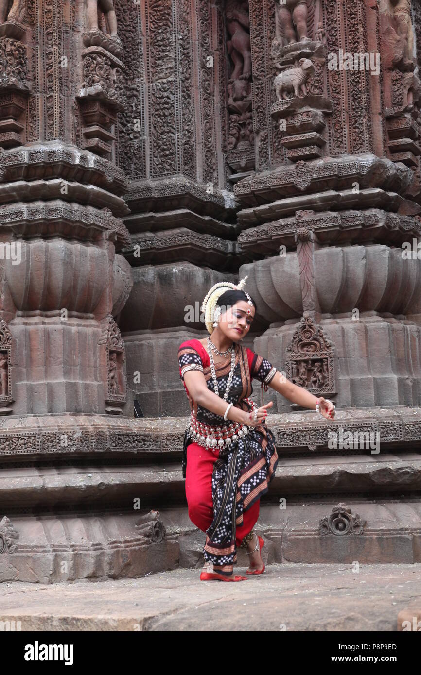 odissi is one of the eight classical dance forms of india,from the state of odisha.here the dancer poses before temples with sculptures Stock Photo
