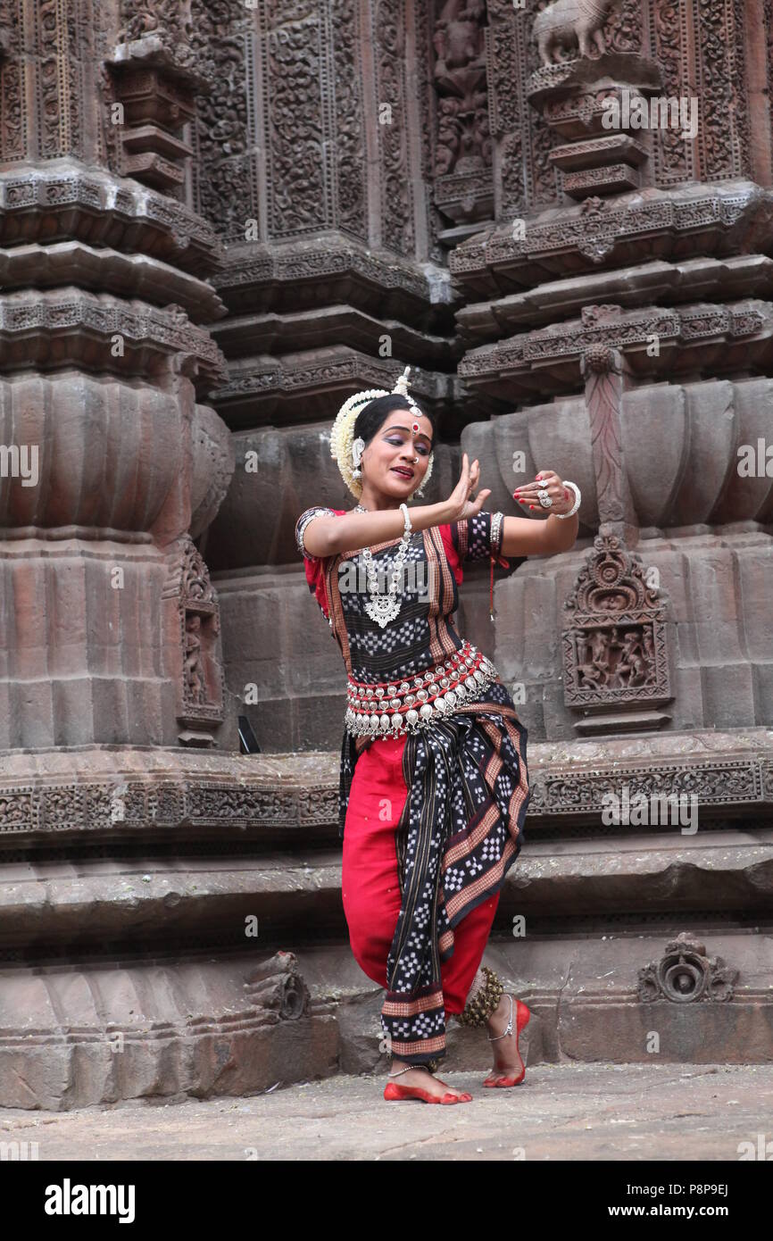 odissi is one of the eight classical dance forms of india,from the state of odisha.here the dancer poses before temples with sculptures Stock Photo