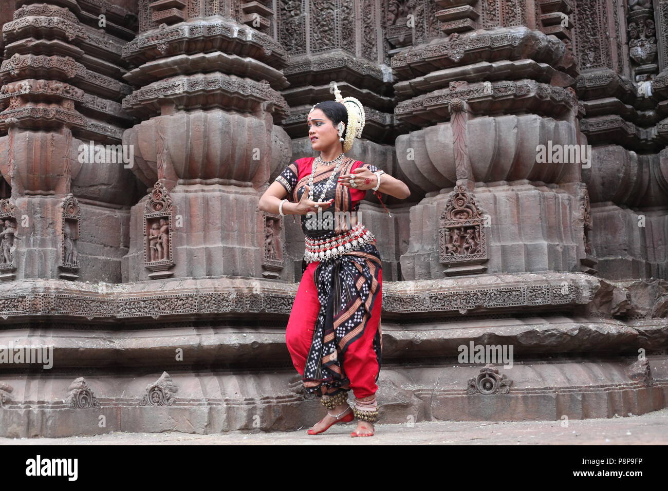 odissi is one of the eight classical dance forms of india,from the state of odisha.here the dancer poses before temples with sculptures Stock Photo