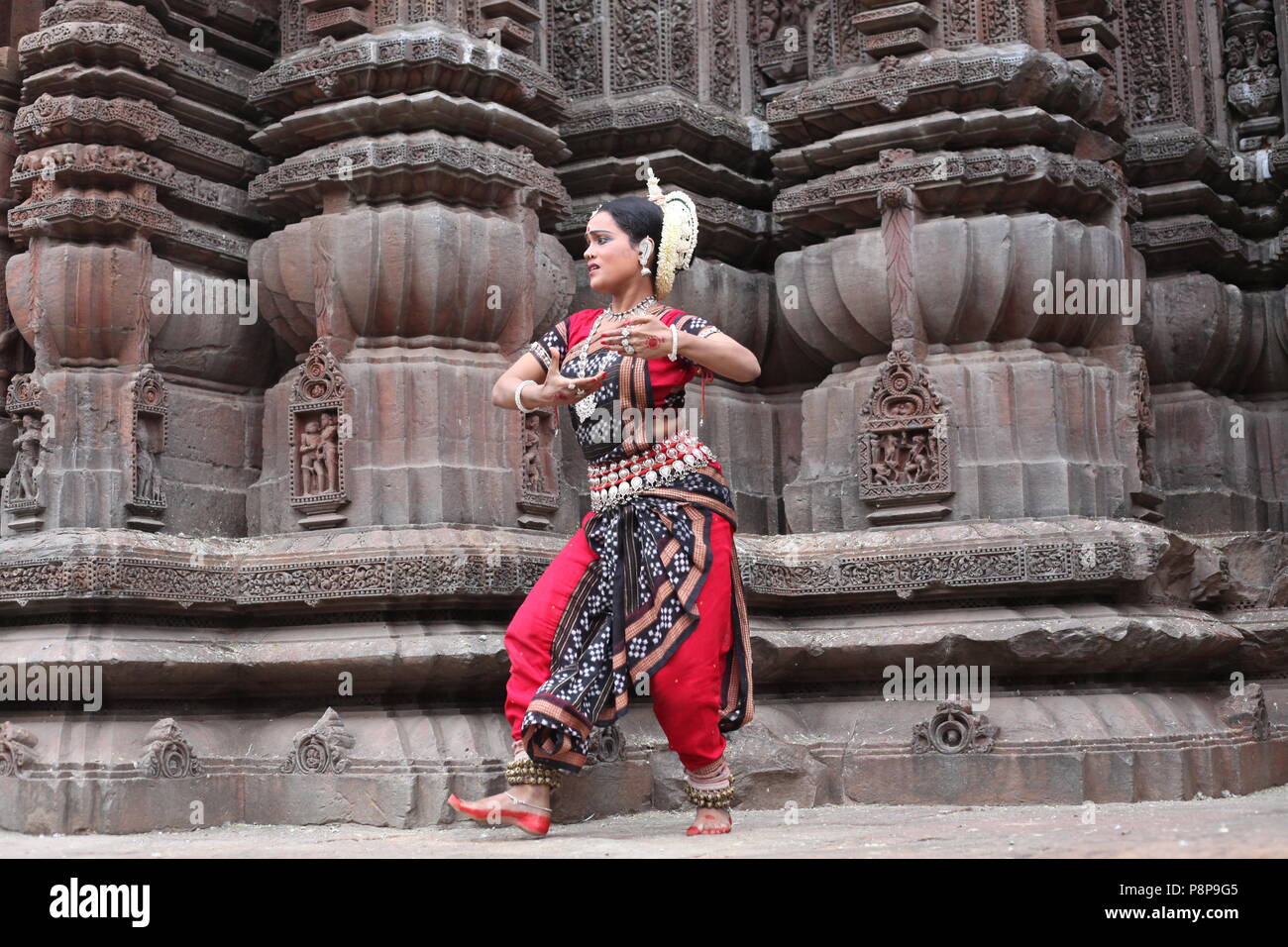 odissi is one of the eight classical dance forms of india,from the state of odisha.here the dancer poses before temples with sculptures Stock Photo
