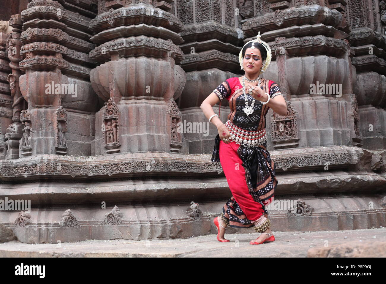 odissi is one of the eight classical dance forms of india,from the state of odisha.here the dancer poses before temples with sculptures Stock Photo