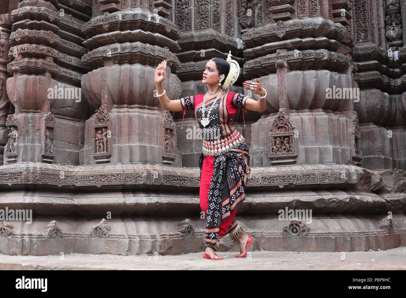 odissi is one of the eight classical dance forms of india,from the state of odisha.here the dancer poses before temples with sculptures Stock Photo