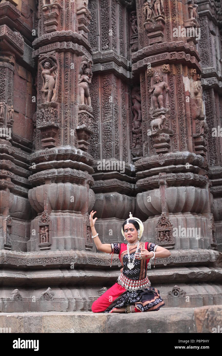 odissi is one of the eight classical dance forms of india,from the state of odisha.here the dancer poses before temples with sculptures Stock Photo