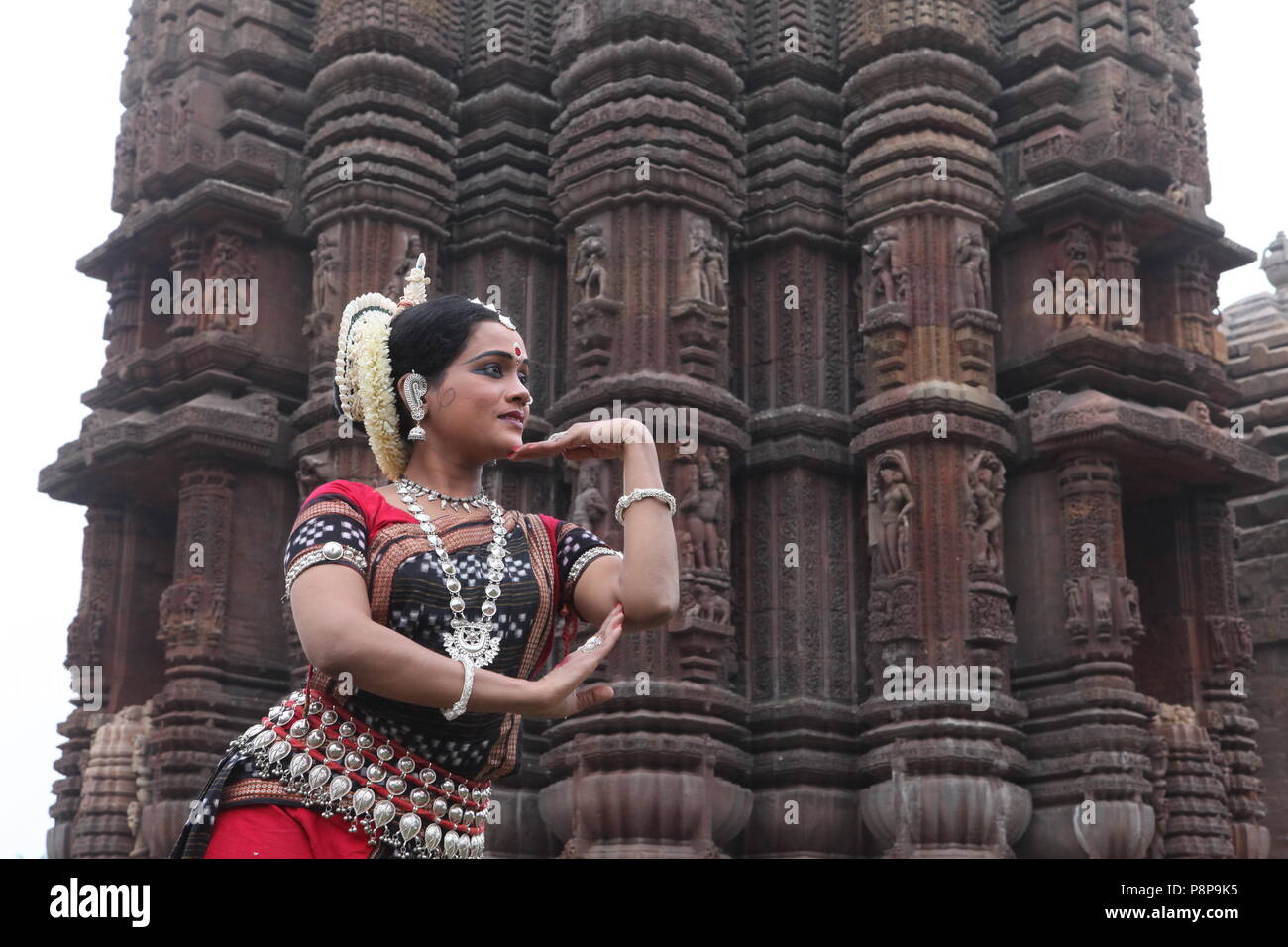 odissi is one of the eight classical dance forms of india,from the state of odisha.here the dancer poses before temples with sculptures Stock Photo