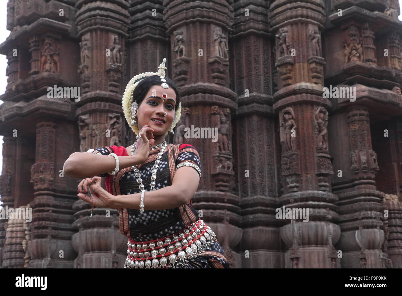 odissi is one of the eight classical dance forms of india,from the state of odisha.here the dancer poses before temples with sculptures Stock Photo