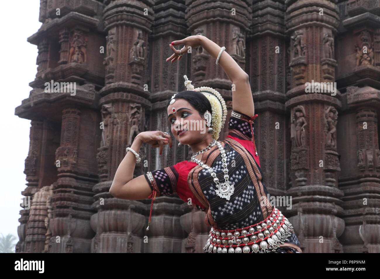 odissi is one of the eight classical dance forms of india,from the state of odisha.here the dancer poses before temples with sculptures Stock Photo