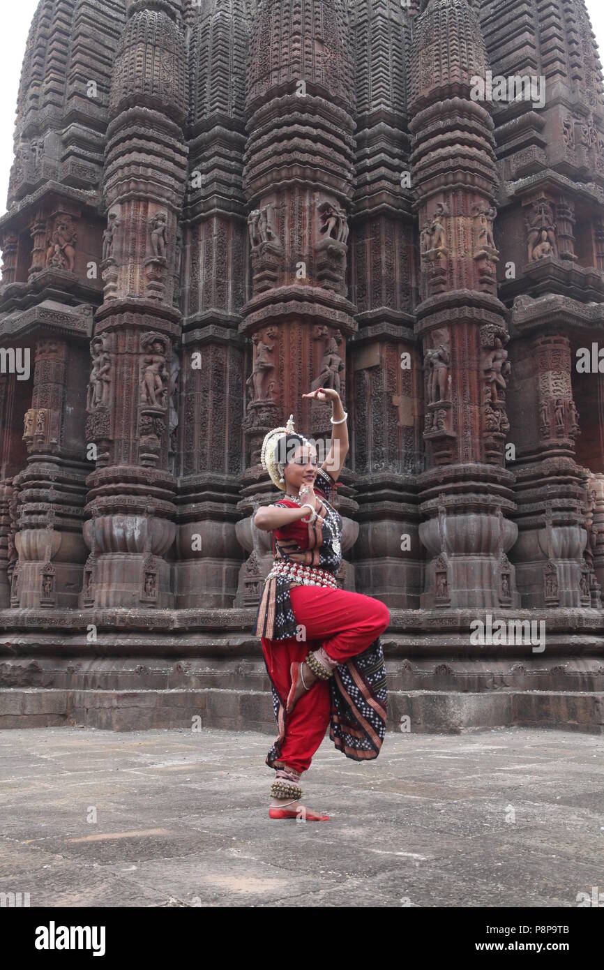 odissi is one of the eight classical dance forms of india,from the state of odisha.here the dancer poses before temples with sculptures Stock Photo