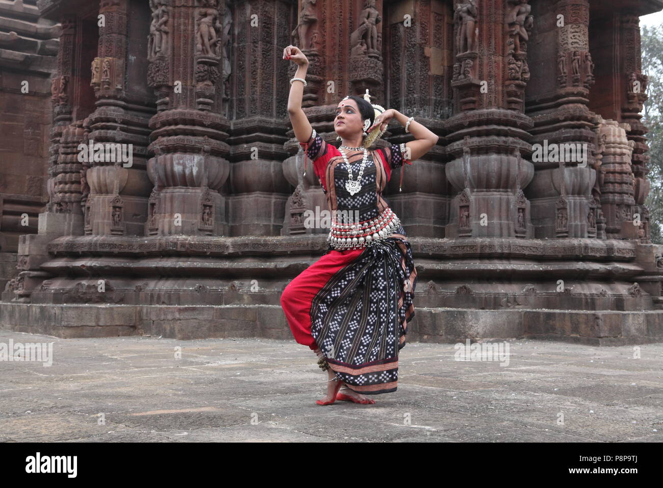 odissi is one of the eight classical dance forms of india,from the state of odisha.here the dancer poses before temples with sculptures Stock Photo
