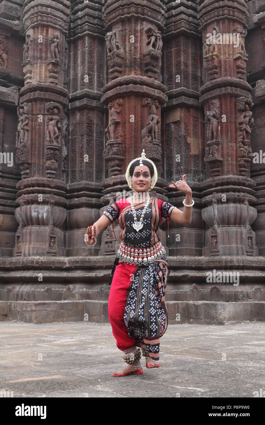 odissi is one of the eight classical dance forms of india,from the state of odisha.here the dancer poses before temples with sculptures Stock Photo