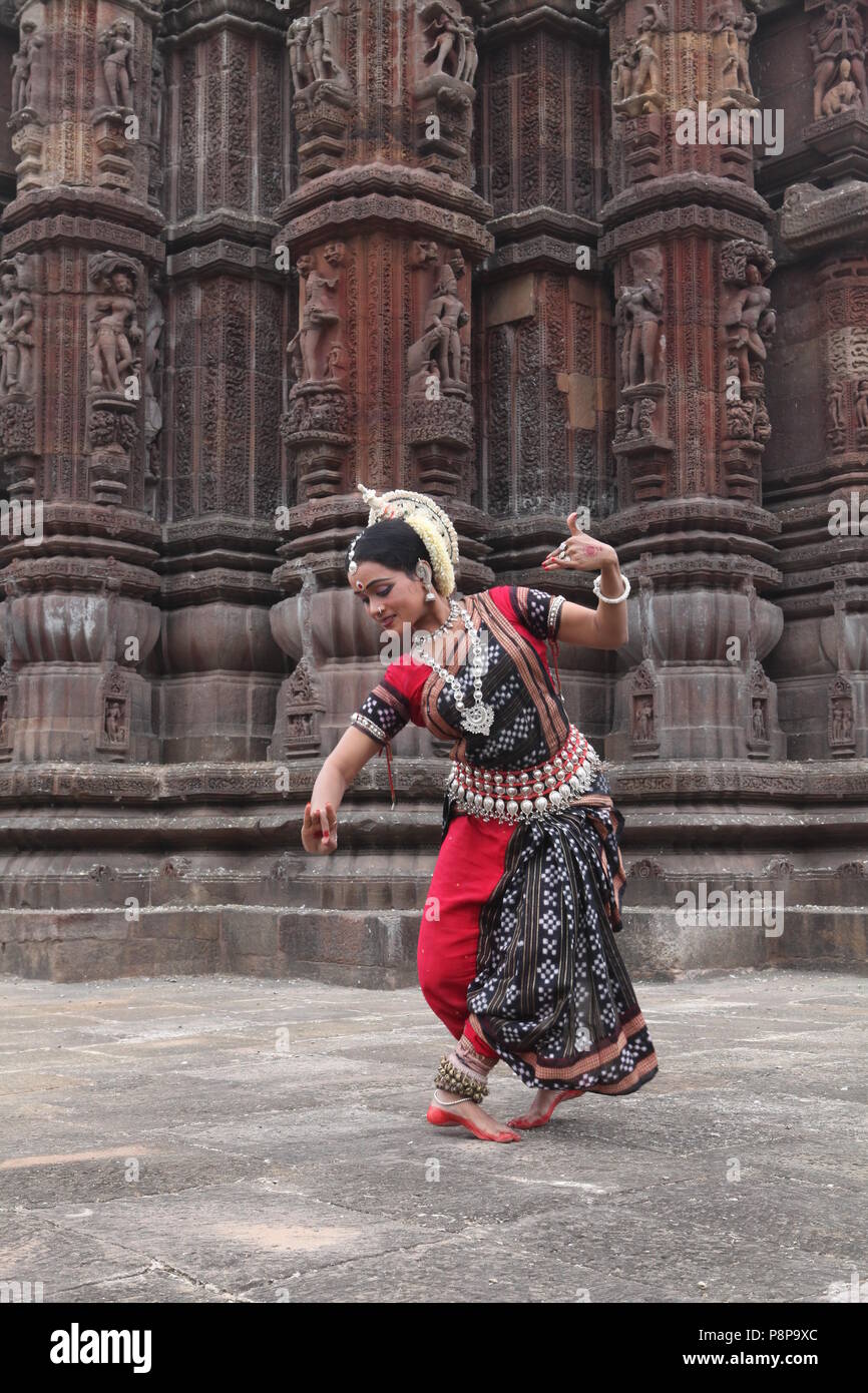 odissi is one of the eight classical dance forms of india,from the state of odisha.here the dancer poses before temples with sculptures Stock Photo