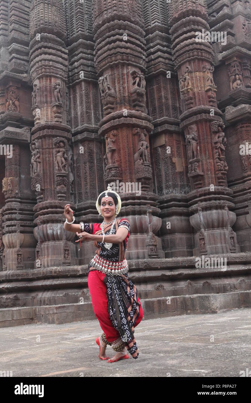 odissi is one of the eight classical dance forms of india,from the state of odisha.here the dancer poses before temples with sculptures Stock Photo