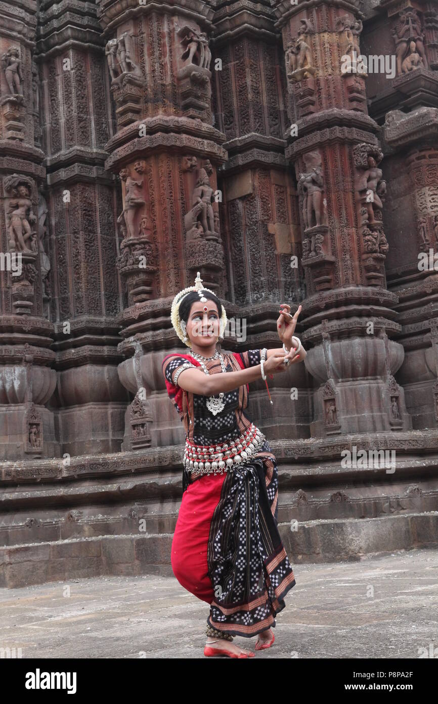 odissi is one of the eight classical dance forms of india,from the state of odisha.here the dancer poses before temples with sculptures Stock Photo
