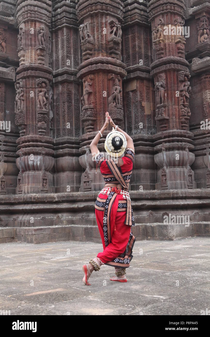 odissi is one of the eight classical dance forms of india,from the state of odisha.here the dancer poses before temples with sculptures Stock Photo