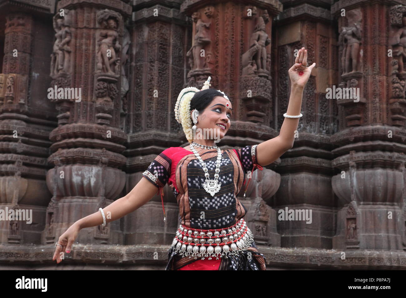 odissi is one of the eight classical dance forms of india,from the state of odisha.here the dancer poses before temples with sculptures Stock Photo