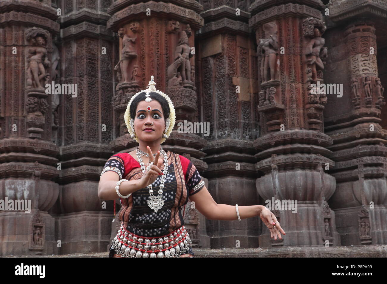 odissi is one of the eight classical dance forms of india,from the state of odisha.here the dancer poses before temples with sculptures Stock Photo