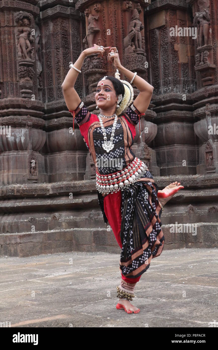 odissi is one of the eight classical dance forms of india,from the state of odisha.here the dancer poses before temples with sculptures Stock Photo
