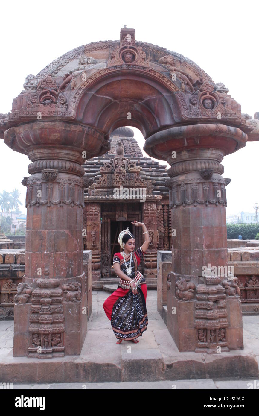 odissi is one of the eight classical dance forms of india,from the state of odisha.here the dancer poses before temples with sculptures Stock Photo