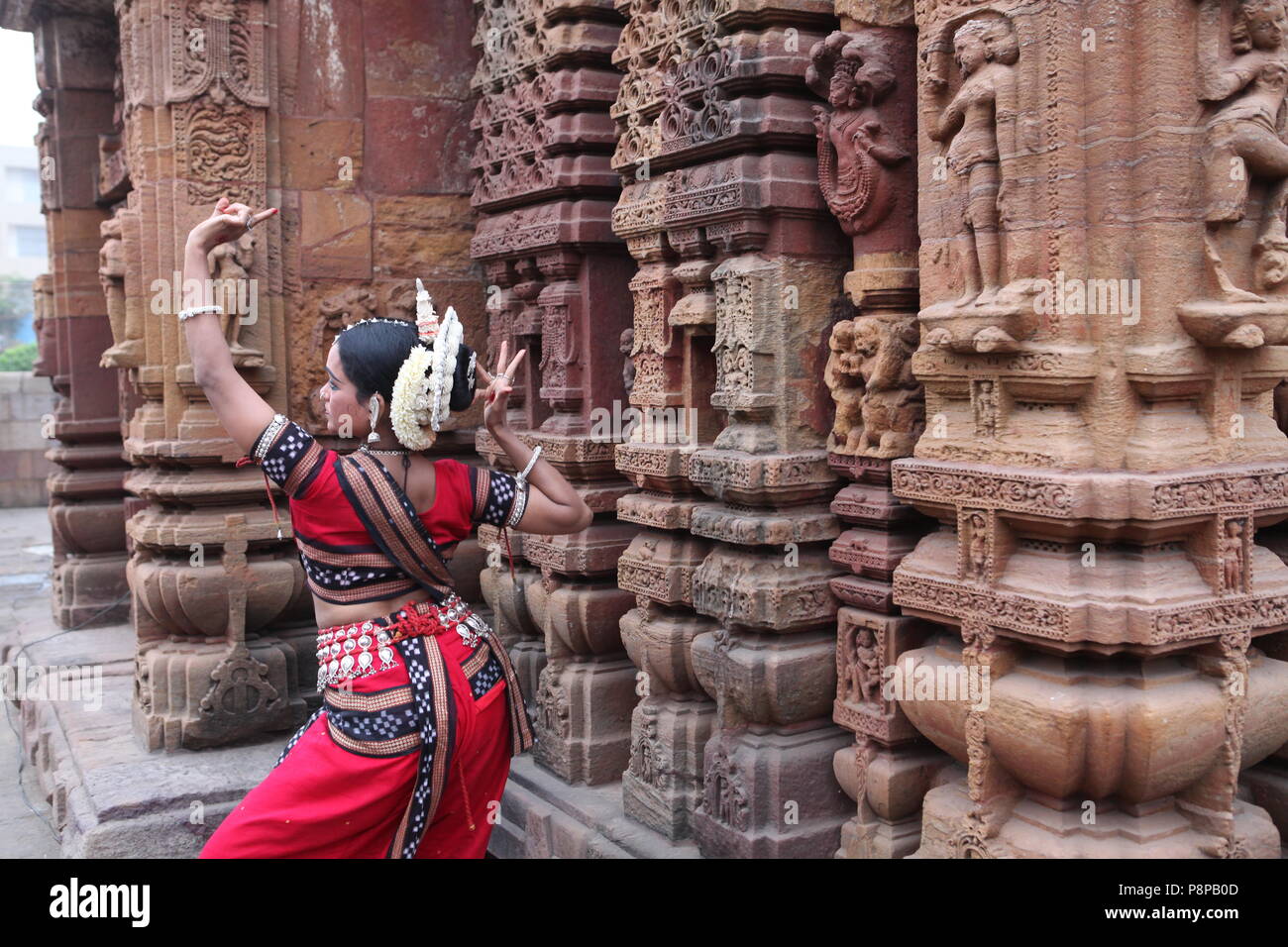 odissi is one of the eight classical dance forms of india,from the state of odisha.here the dancer poses before temples with sculptures Stock Photo