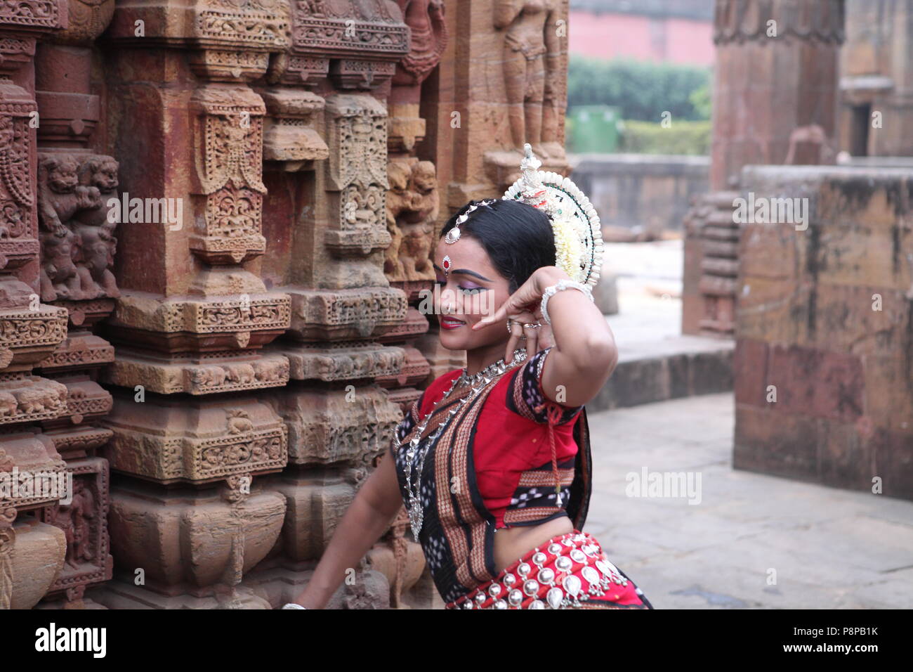odissi is one of the eight classical dance forms of india,from the state of odisha.here the dancer poses before temples with sculptures Stock Photo