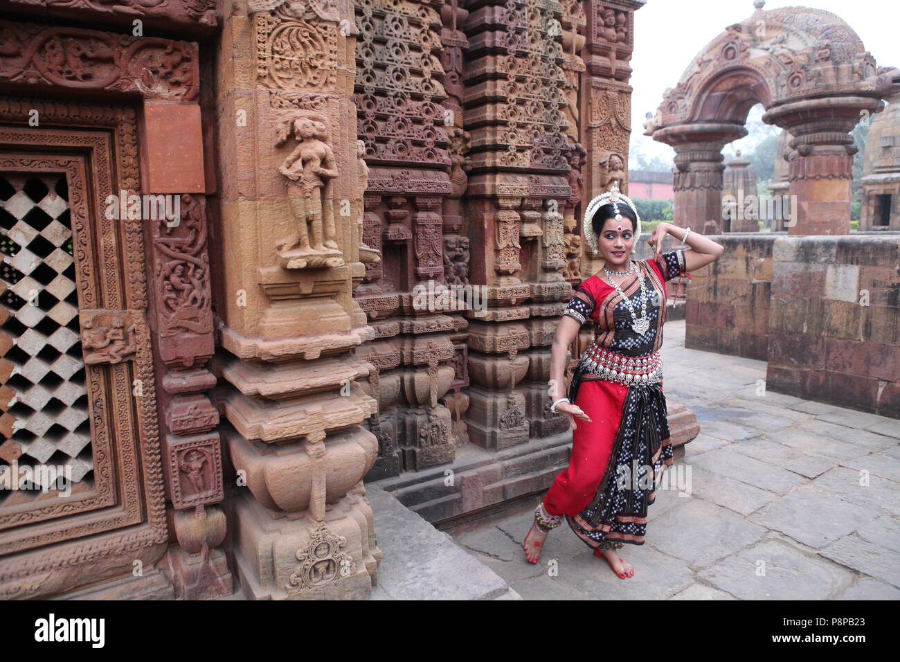 odissi is one of the eight classical dance forms of india,from the state of odisha.here the dancer poses before temples with sculptures Stock Photo