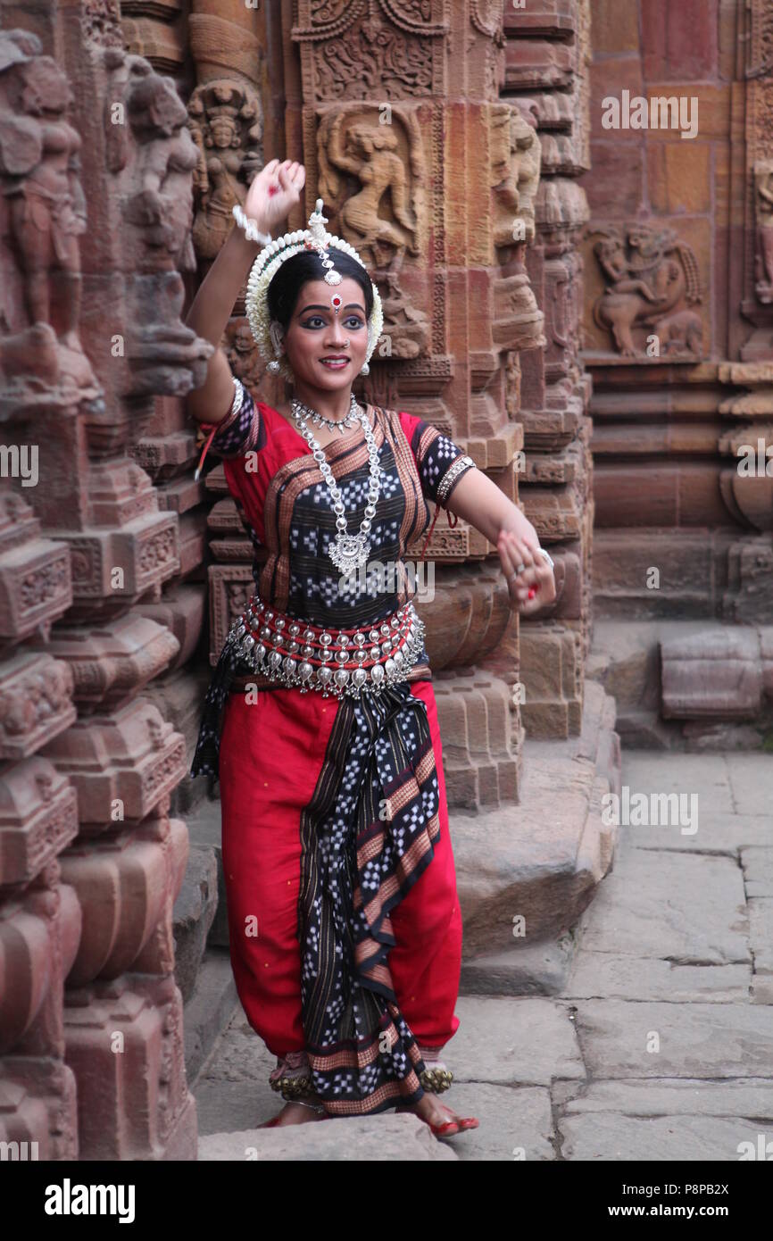 odissi is one of the eight classical dance forms of india,from the state of odisha.here the dancer poses before temples with sculptures Stock Photo