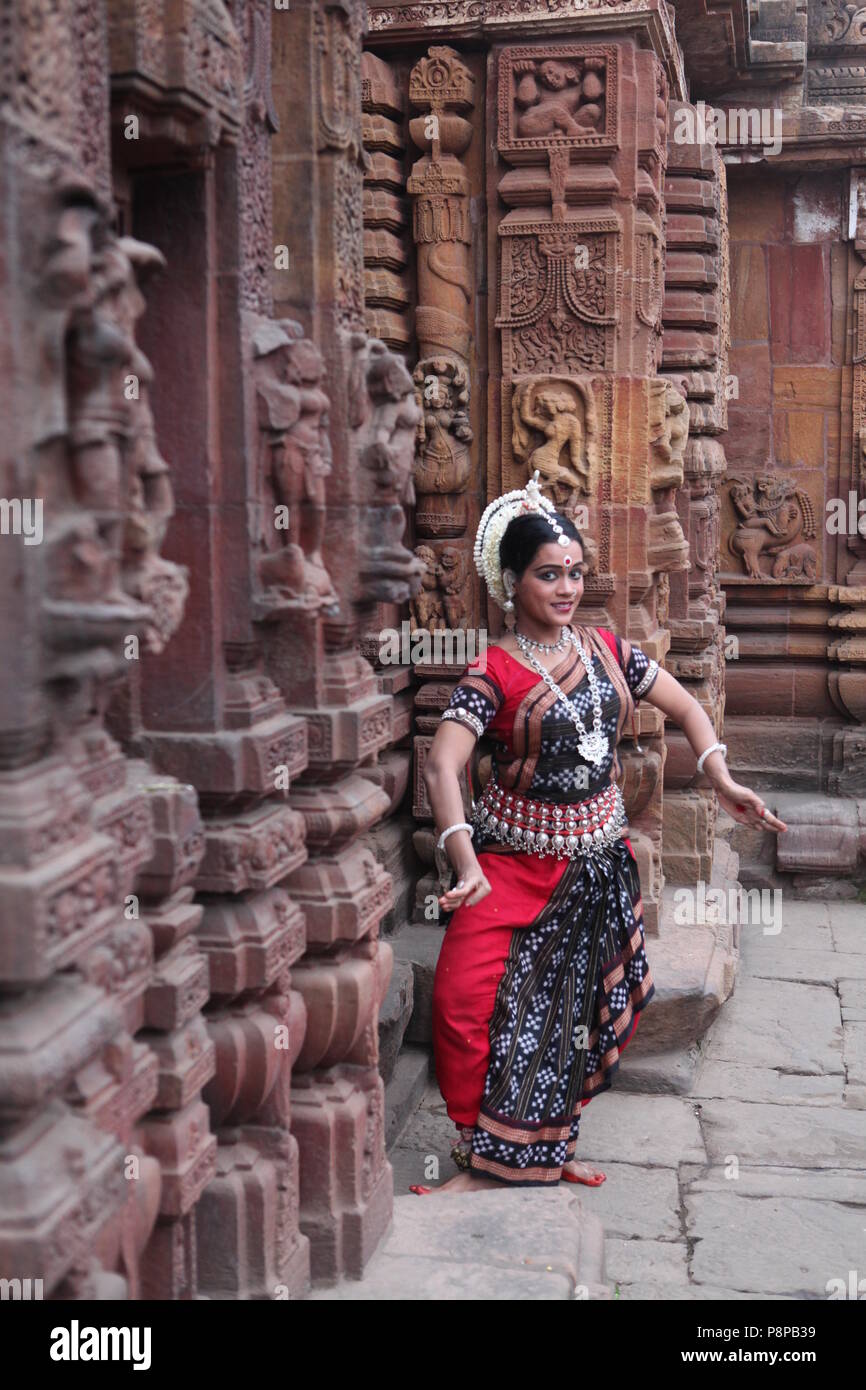 odissi is one of the eight classical dance forms of india,from the state of odisha.here the dancer poses before temples with sculptures Stock Photo