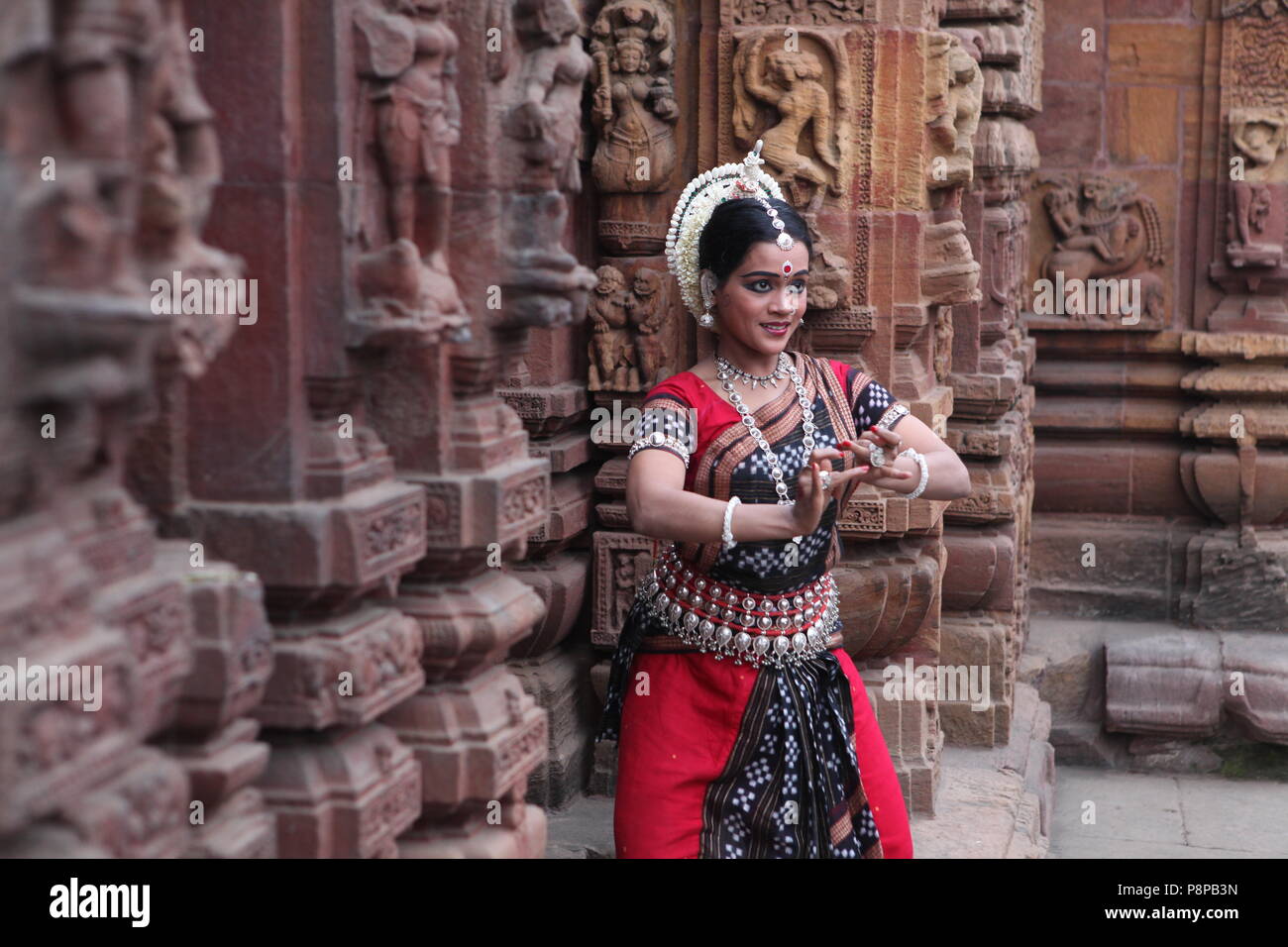 odissi is one of the eight classical dance forms of india,from the state of odisha.here the dancer poses before temples with sculptures Stock Photo