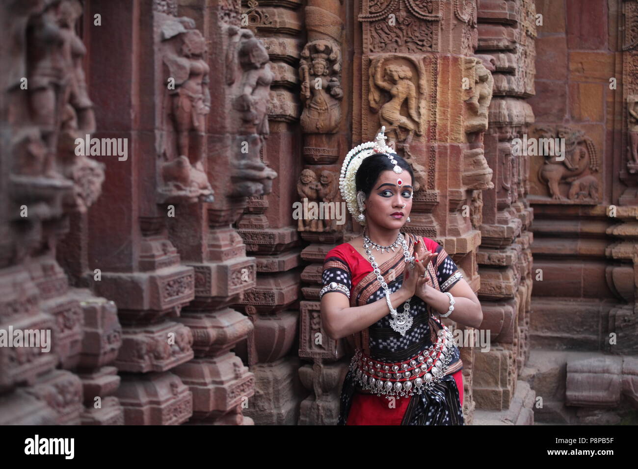 odissi is one of the eight classical dance forms of india,from the state of odisha.here the dancer poses before temples with sculptures Stock Photo