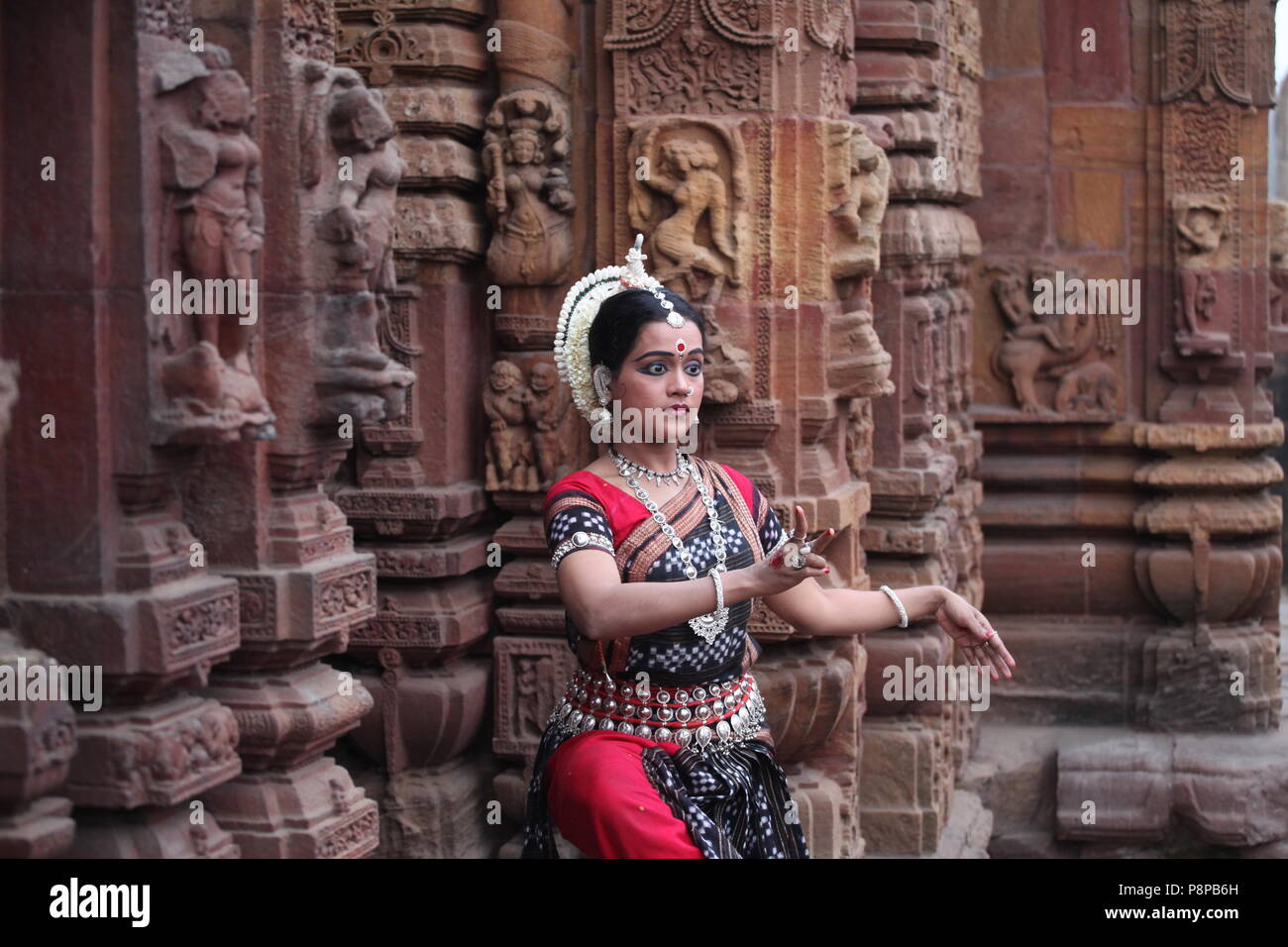 odissi is one of the eight classical dance forms of india,from the state of odisha.here the dancer poses before temples with sculptures Stock Photo