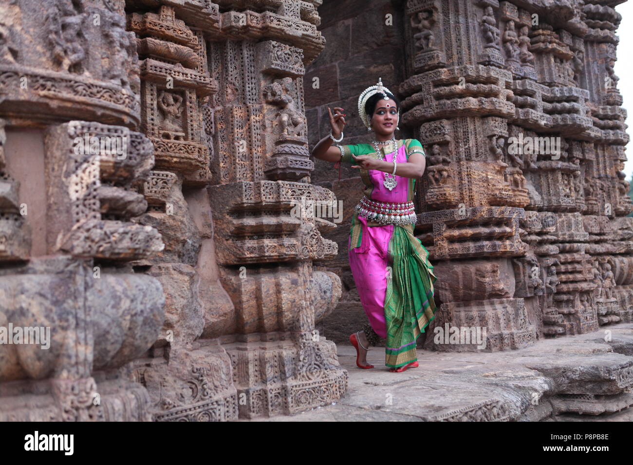 odissi is one of the eight classical dance forms of india,from the state of odisha.here the dancer poses before temples with sculptures Stock Photo