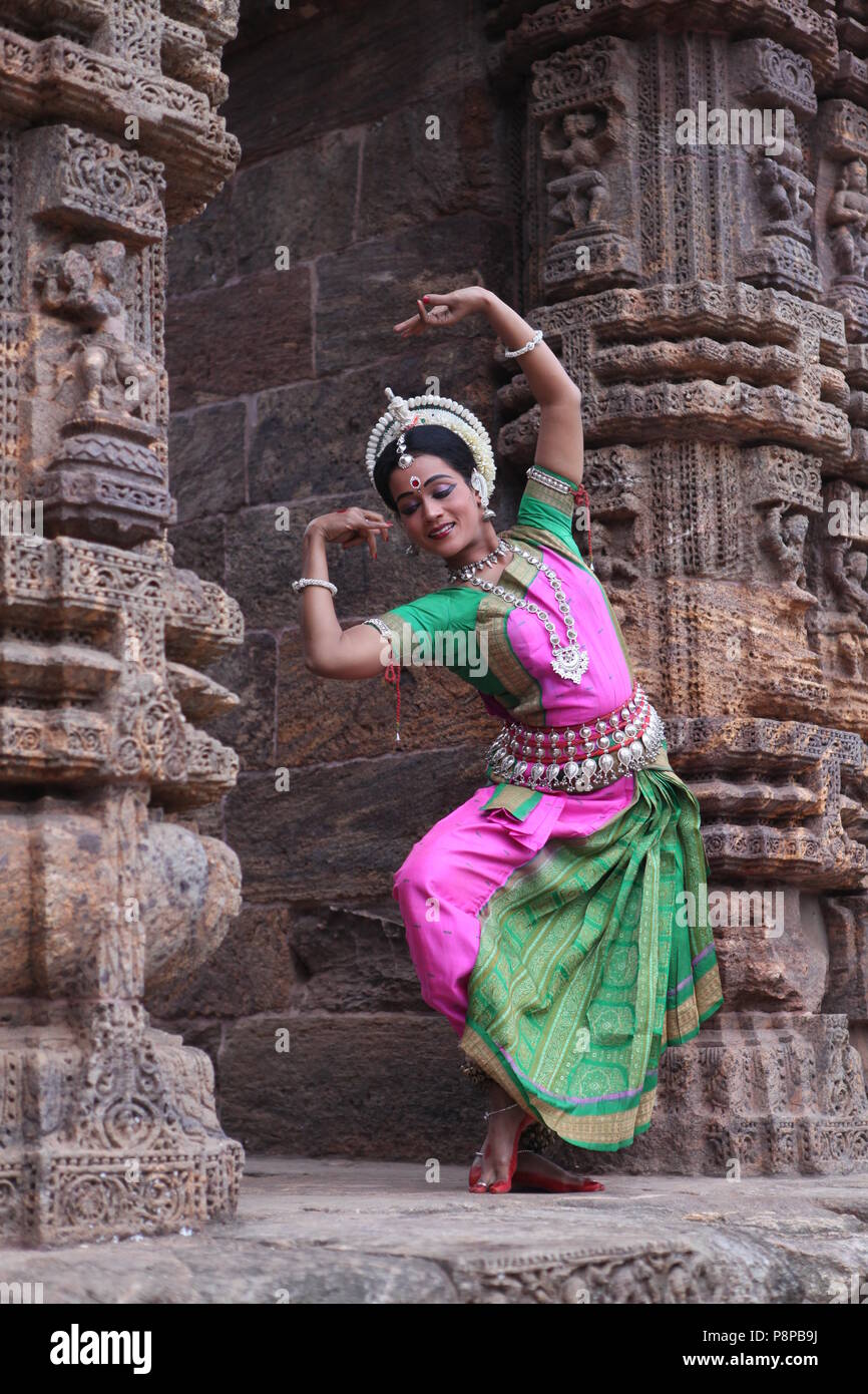 odissi is one of the eight classical dance forms of india,from the state of odisha.here the dancer poses before temples with sculptures Stock Photo