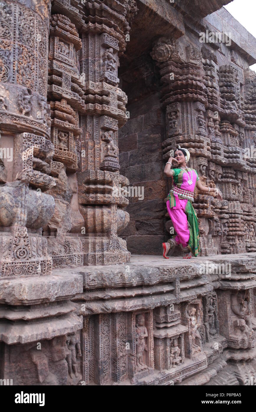 odissi is one of the eight classical dance forms of india,from the state of odisha.here the dancer poses before temples with sculptures Stock Photo