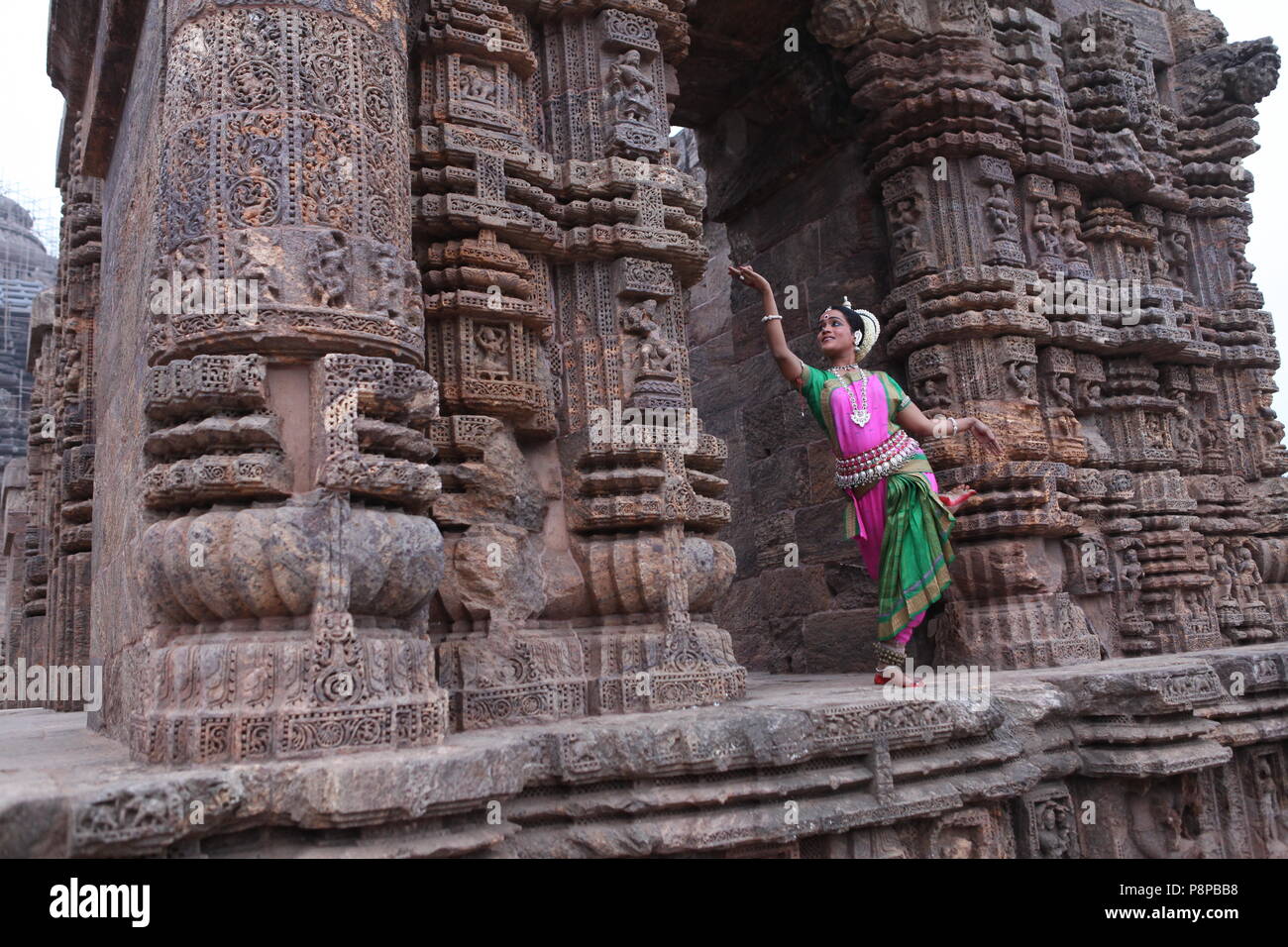 odissi is one of the eight classical dance forms of india,from the state of odisha.here the dancer poses before temples with sculptures Stock Photo