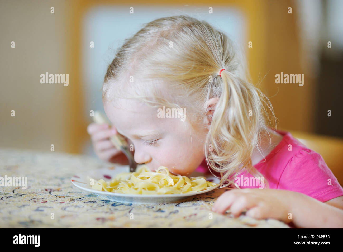 Cute funny little girl eating spaghetti Stock Photo - Alamy