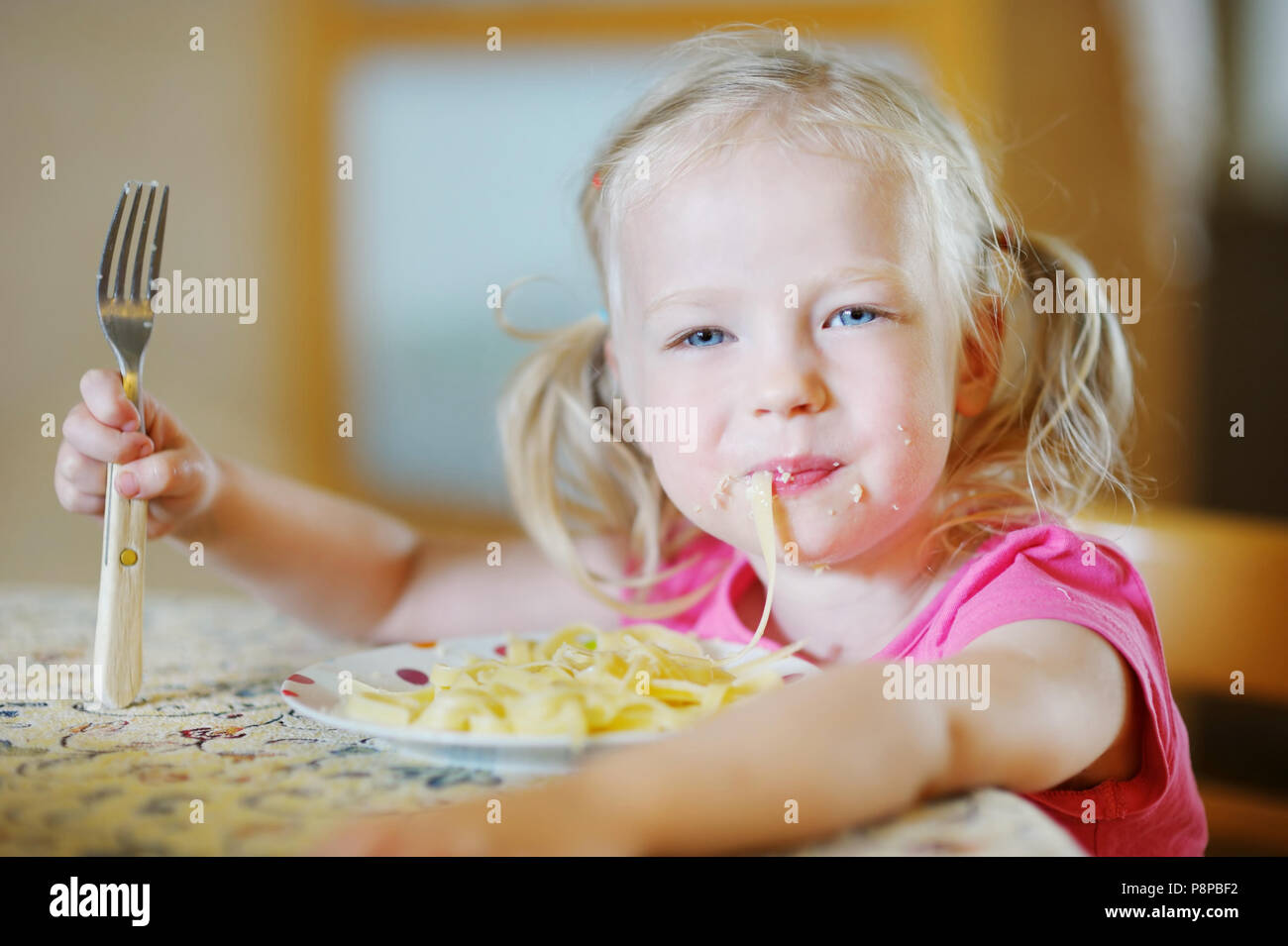 Cute funny little girl eating spaghetti Stock Photo - Alamy