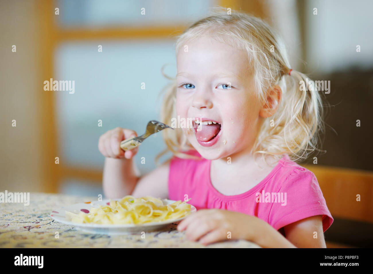 Cute funny little girl eating spaghetti Stock Photo - Alamy