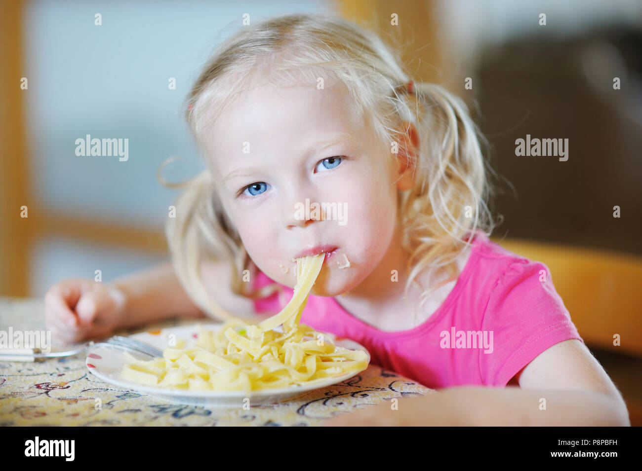 Cute funny little girl eating spaghetti Stock Photo - Alamy