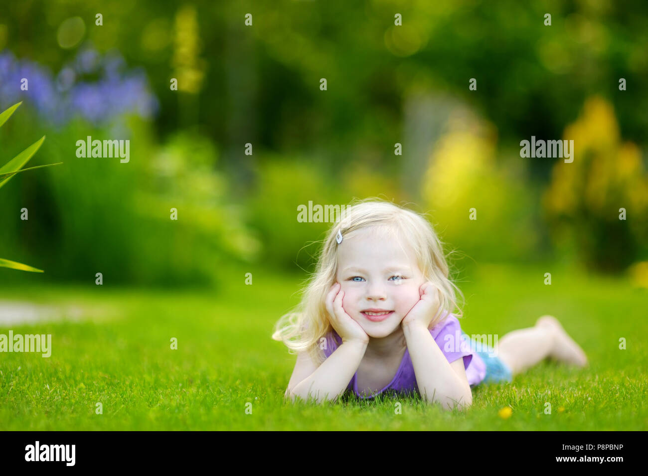 Cute little girl laying in the grass on a sunny summer day Stock Photo ...