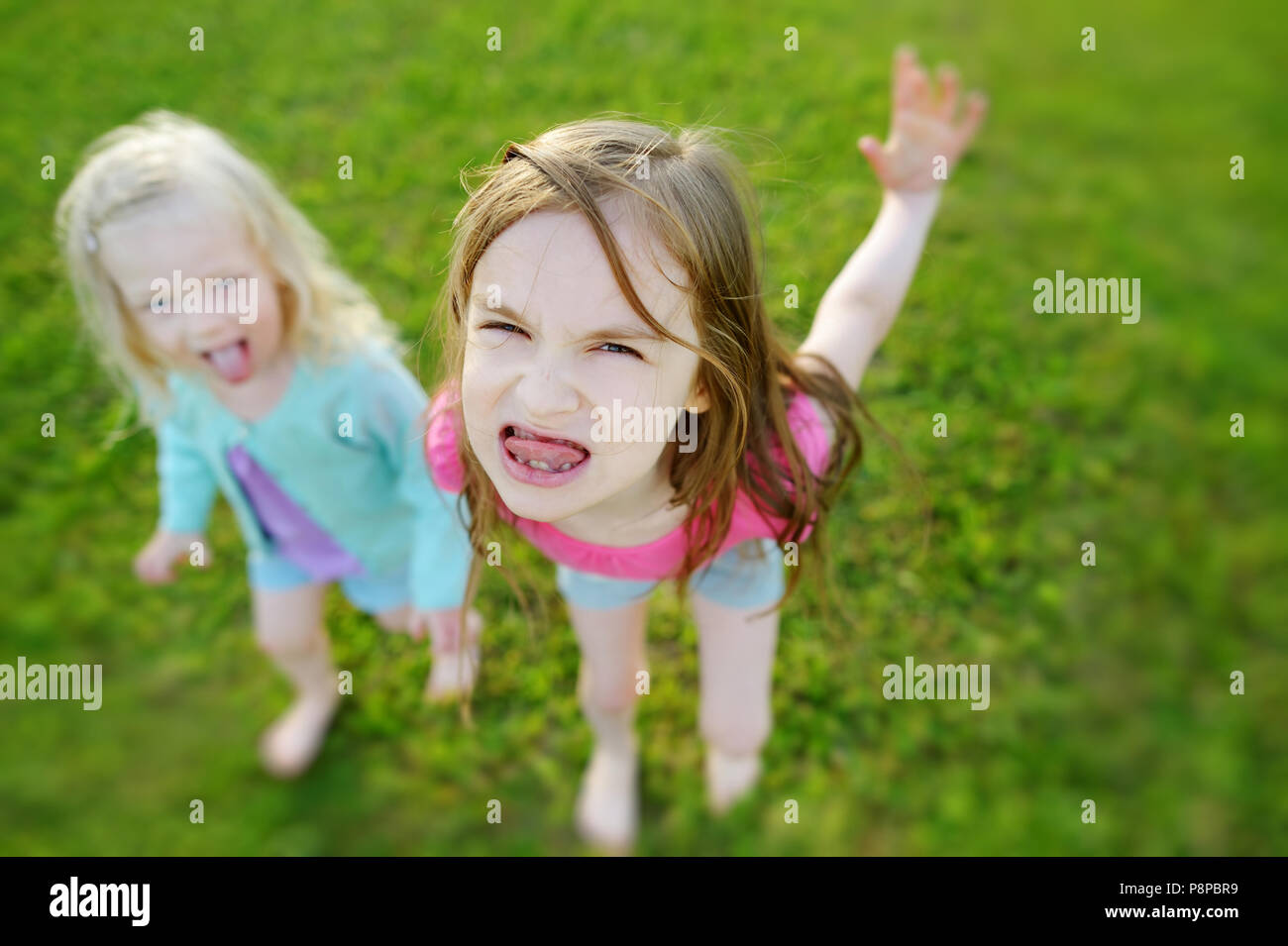 Two little sisters making funny faces outdoors Stock Photo