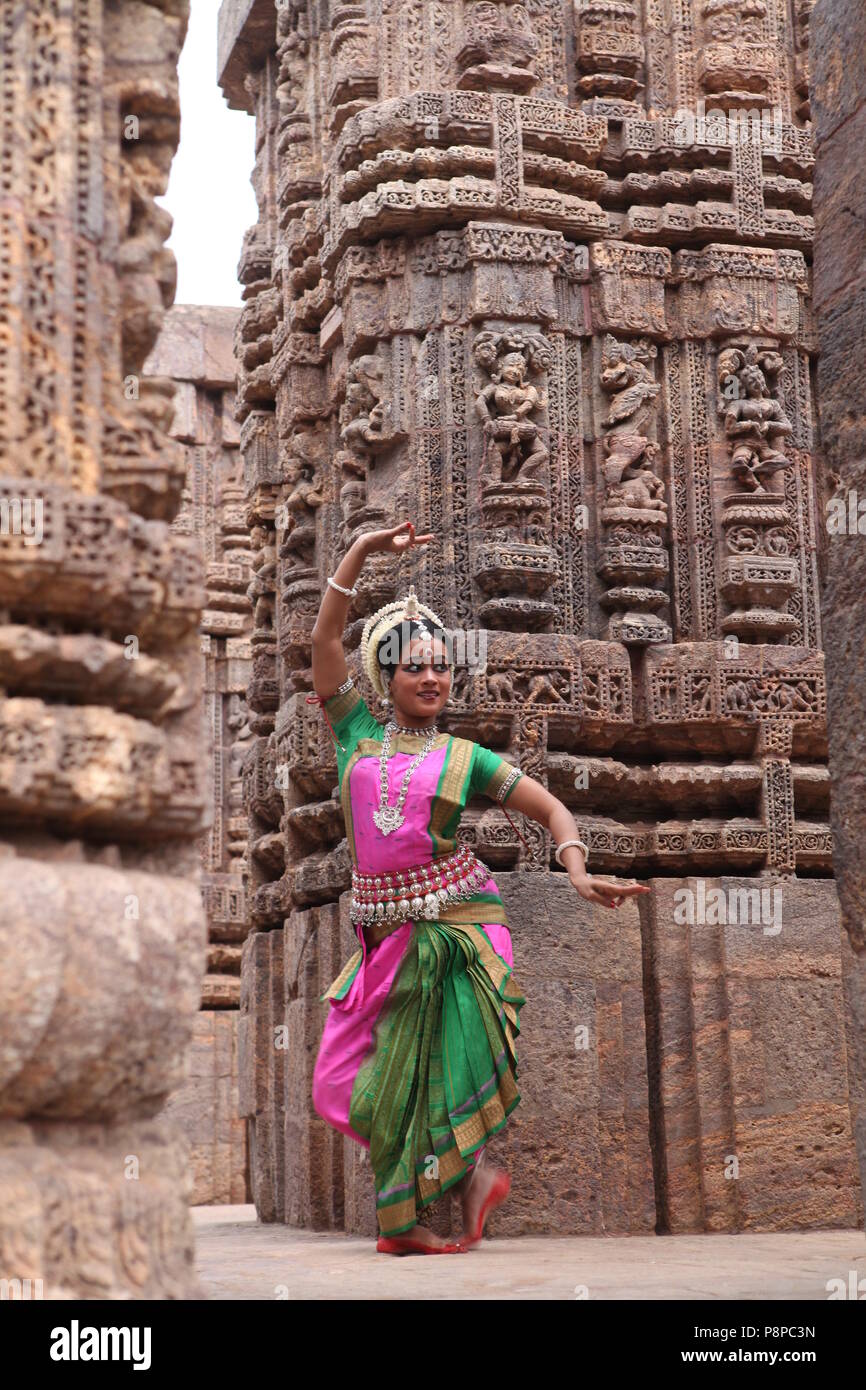 odissi is one of the eight classical dance forms of india,from the state of odisha.here the dancer poses before temples with sculptures Stock Photo