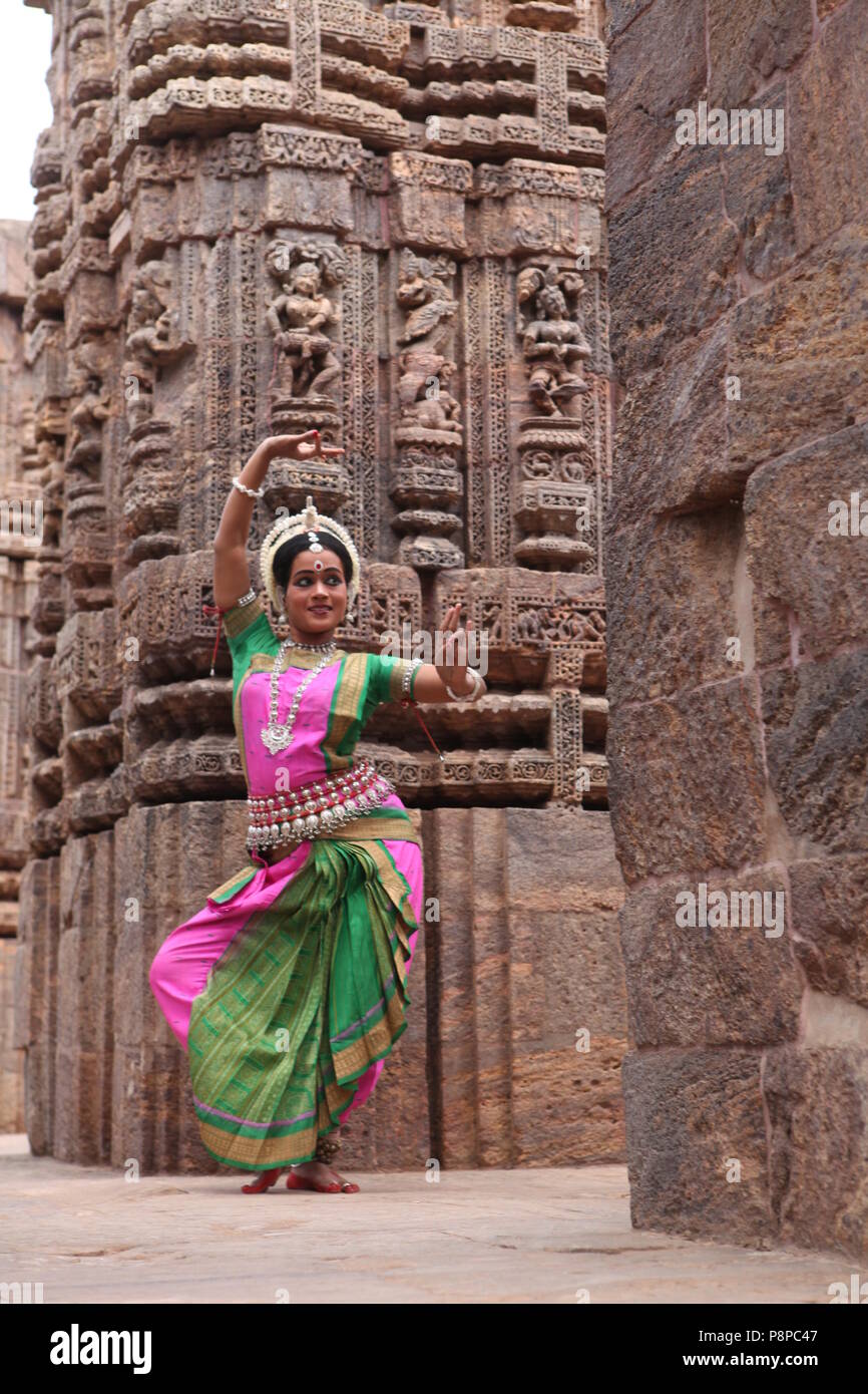 odissi is one of the eight classical dance forms of india,from the state of odisha.here the dancer poses before temples with sculptures Stock Photo