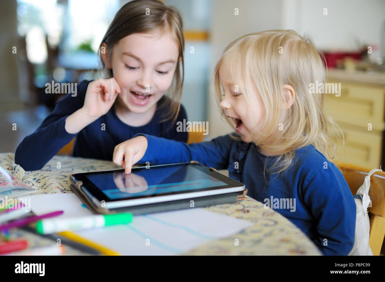 Two adorable little sisters playing with a digital tablet at home Stock ...