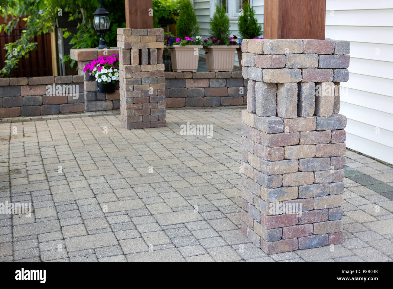Ornamental grey brickwork around wooden pergola legs matching the paving on  the outdoor patio Stock Photo - Alamy