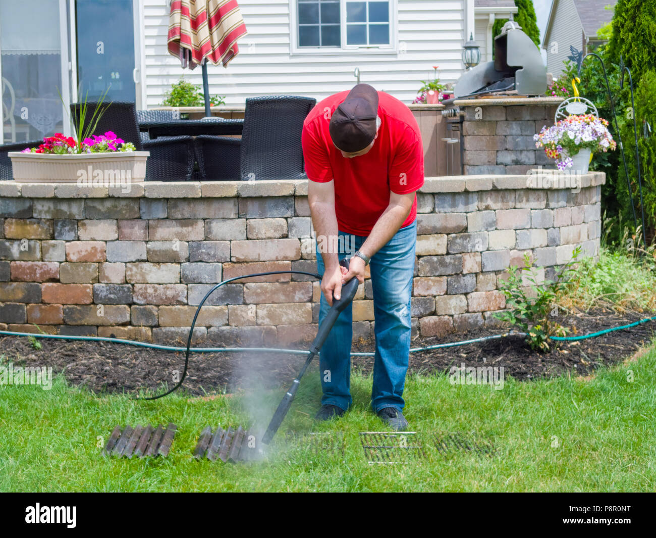 Man pressure cleaning dirty grill plates from a BBQ using a hosepipe