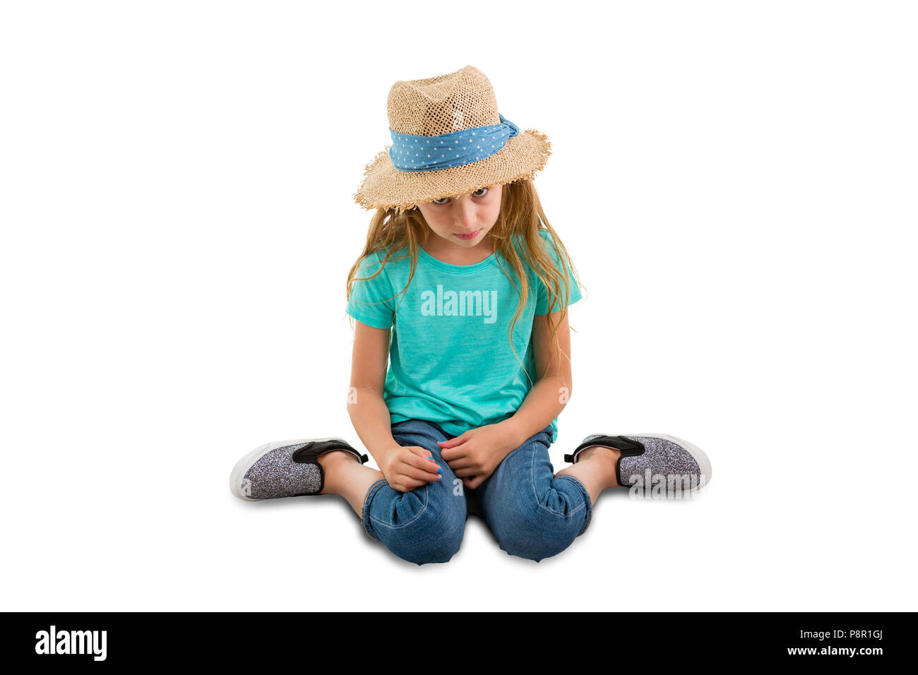 Guilty little girl sitting with her head bowed looking very contrite as she gazes down at the floor isolated on white with copy space Stock Photo