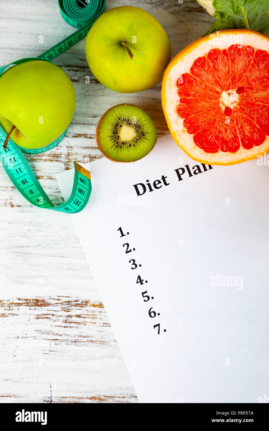 Food and sheet of paper with a diet plan on a wooden background ...